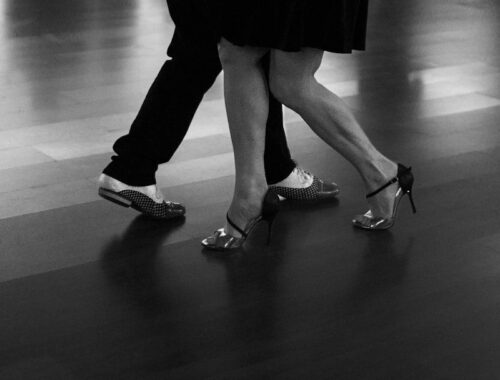 Close-up of dancers’ feet stepping across a polished floor