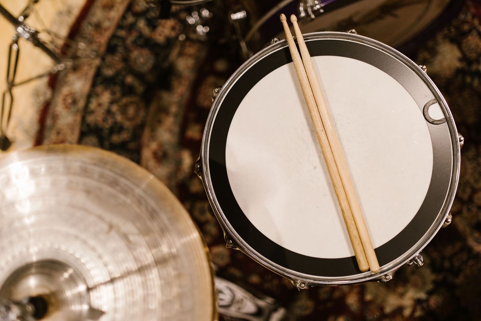 Overhead view of a snare drum and sticks beside a cymbal