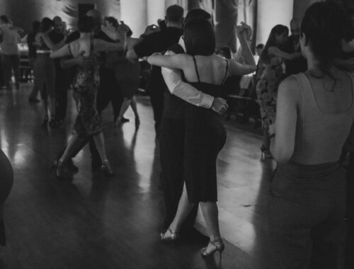 Dancers navigating a crowded ballroom floor in close partner holds